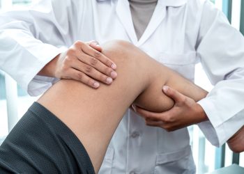 Female Physiotherapist working examining treating injured leg of patient, Doing exercises the Rehabilitation therapy pain his in clinic.